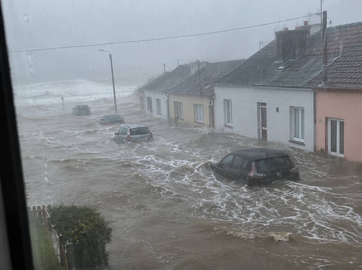 Fala sztormowa zalewająca nadmorską ulicę w czasie ulewy, woda do połowy drzwi domów i samochody po koła w wodzie