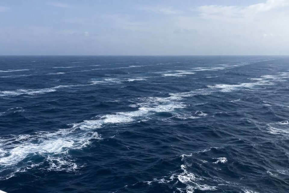 Otwarty ocean z pokładu statku, ciemnoniebieska woda prądu morskiego z pasmami piany ciągnącymi się po horyzont