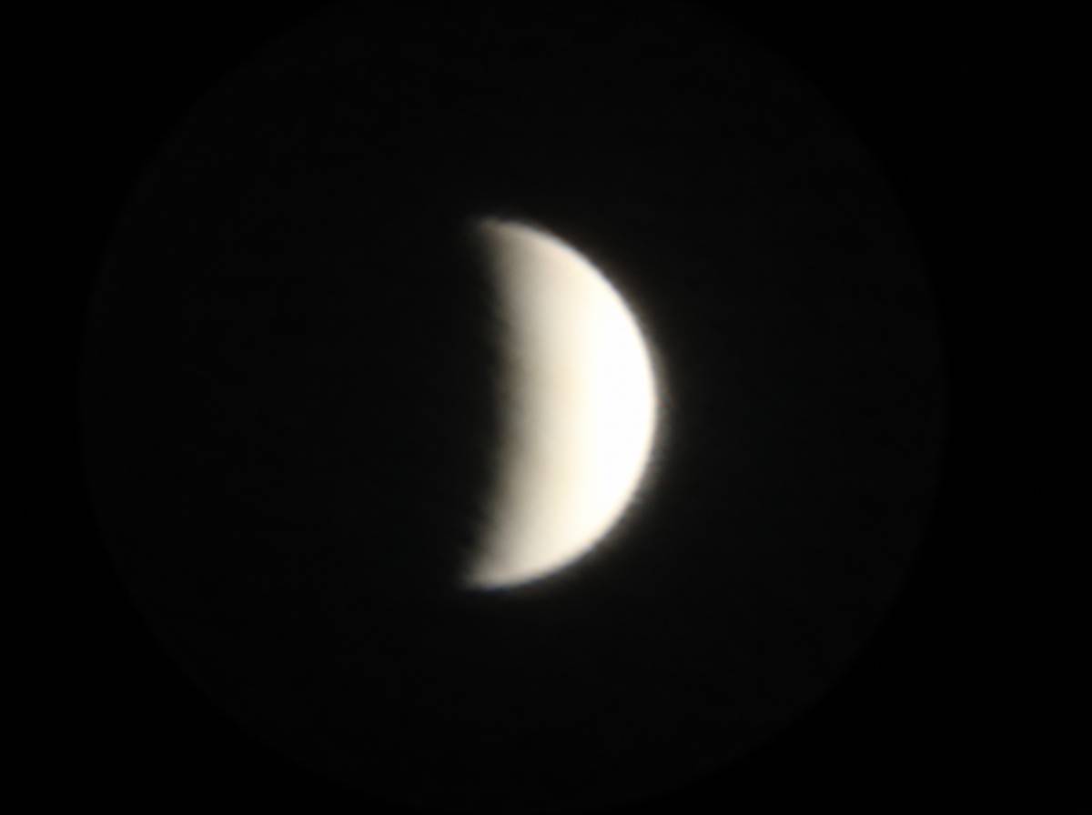 Sierp Wenus w amatorskim teleskopie, oślepiająco biała warstwa chmur na czarnym nocnym niebie