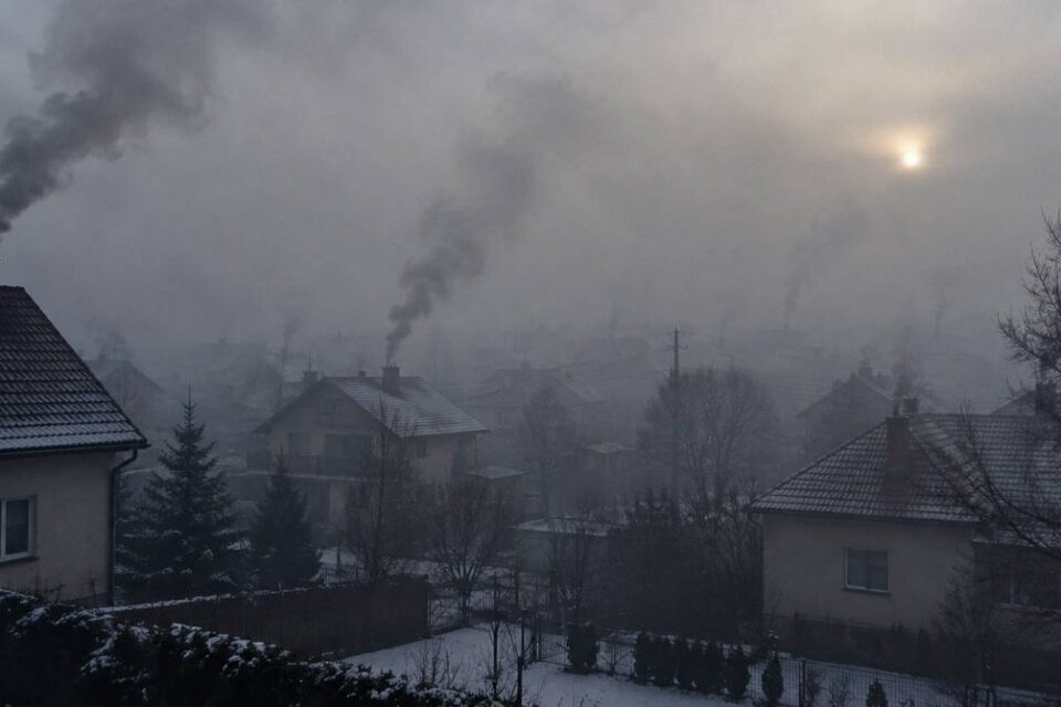 Zimowe osiedle domów jednorodzinnych w smogu, z kominów unosi się dym z domowych pieców na węgiel