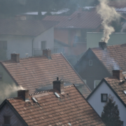 Ciemny dym ulatujący z komina na dachu domu